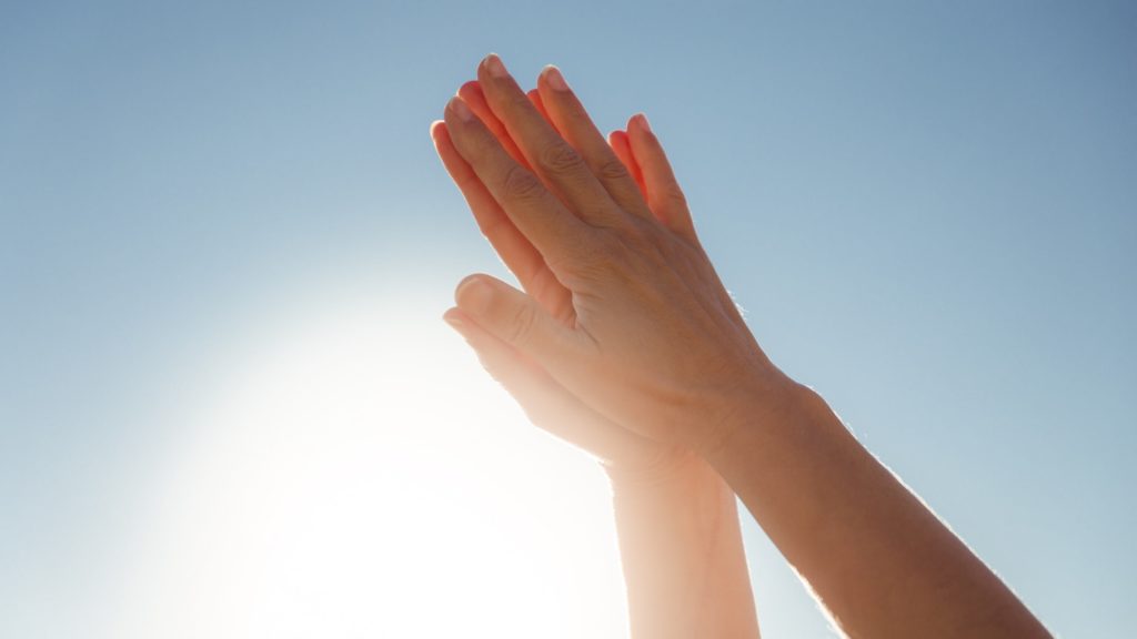 Hands raised to the sky in prayer position